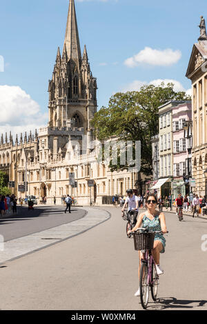 Looking along High St towards the Church of St Mary as cyclists ride along on a beautiful sunny summer's day in the famous university town of Oxford. Stock Photo