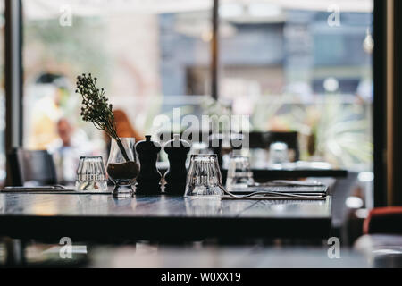 Table set inside a restaurant, selective focus, natural light, windows on the background. Stock Photo