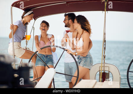 Smiling friends sitting on sailboat deck and having fun. Vacation, travel, sea, friendship and people concept. Stock Photo