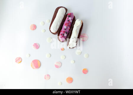 A set of three eclairs with different fillings and design isolate on a white surface decorated with drops of white chocolate, copyspace Stock Photo