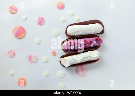 A set of three eclairs with different fillings and design isolate on a white surface decorated with drops of white chocolate, copyspace Stock Photo