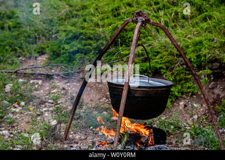 Cauldron or camping kettle over open fire outdoors Stock Photo