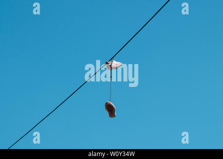 one pair of shoes hanging from a wire  - Stock Photo