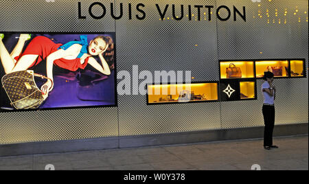 kuala lumpur - 2008.04.16: a young woman holding her mobile phone  standing in front of a louis vuitton boutique at petronas towers klcc shopping mall Stock Photo