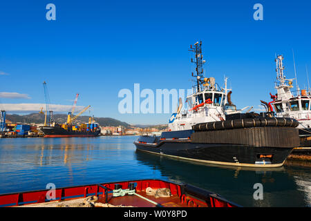 Two tugboats and containers ship docked in the harbor of La Spezia, Liguria, Italy Stock Photo