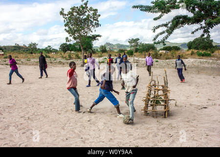 Children playing football barefoot with a handmade ball made with rags in a sandy field in rural Mozambique Stock Photo