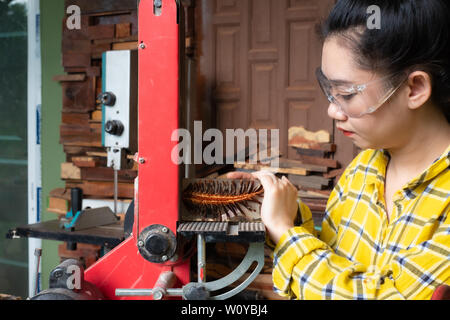 Carpenter women standing is craft working polishing resin pin cone at a work bench with sandpaper polish machine power tools Stock Photo