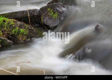 water rushing over mossy stones in a small creek Stock Photo