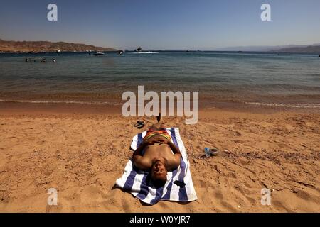 (190628) -- AQABA (JORDAN), June 28, 2019 (Xinhua) -- A tourist enjoys leisure on the beach of the Red Sea in the southern port city of Aqaba, Jordan, on June 28, 2019. Aqaba attracts tourists from Jordan and abroad to enjoy their summer holidays with its famous beaches and various water sports. (Xinhua/Mohammad Abu Ghosh) Stock Photo