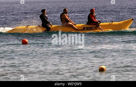 (190628) -- AQABA (JORDAN), June 28, 2019 (Xinhua) -- Tourists ride a banana boat in the Red Sea in the southern port city of Aqaba, Jordan, on June 28, 2019. Aqaba attracts tourists from Jordan and abroad to enjoy their summer holidays with its famous beaches and various water sports. (Xinhua/Mohammad Abu Ghosh) Stock Photo