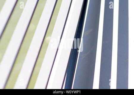 The close-up of the white-painted crossbars of a bridge railing, which casts symmetrical shadows. Stock Photo