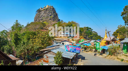 POPA, MYANMAR - FEBRUARY 26, 2018: The way to Popa Taung Kalat stretches among the Nat Shrines, shabby houses and market stalls of the town, on Februa Stock Photo