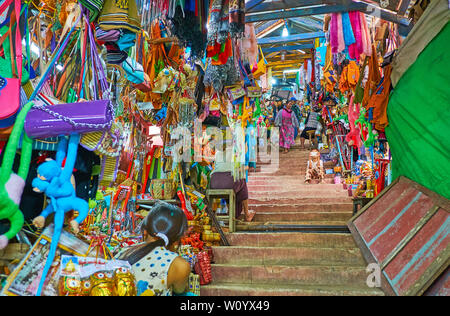 POPA, MYANMAR - FEBRUARY 26, 2018: The long narrow gallery, leading to the Popa Taung Kalat is housing the stalls of the market, full of toys, accesso Stock Photo