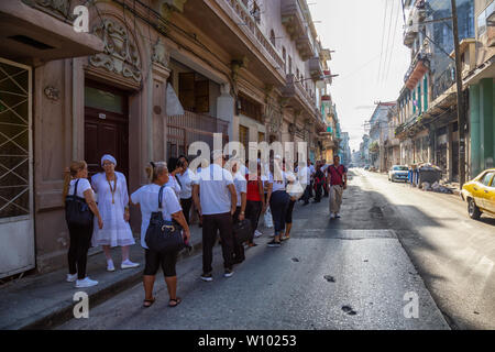 Havana, Cuba - May 13, 2019: Crowd of Cuban People waiting in line for the food in the streets of the Old Havana City during a bright sunny morning. Stock Photo