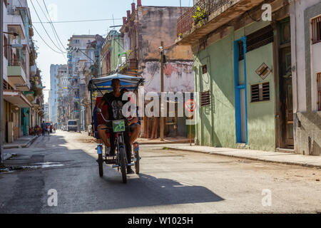 Havana, Cuba - May 13, 2019: Bicycle Taxi Driver riding in the streets of Old Havana City during a vibrant and bright sunny morning. Stock Photo