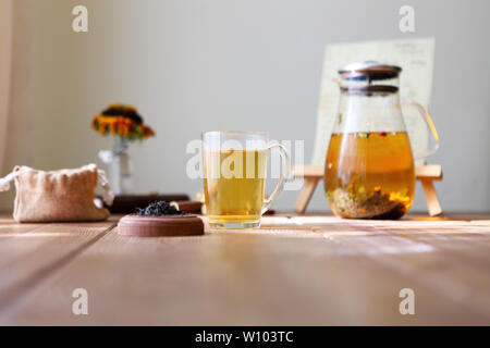 Traditional Asian tea ceremony arrangement. Iron teapot, cups, dried rose buds and candles over wooden table background, selective focus, copy space Stock Photo