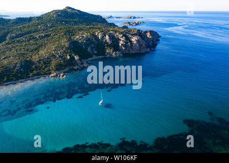 View from above, stunning aerial view of a sailing boat floating on a beautiful turquoise clear sea. Maddalena Archipelago National Park, Sardinia. Stock Photo