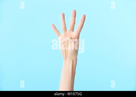 human hand showing number four, isolated on blue background Stock Photo