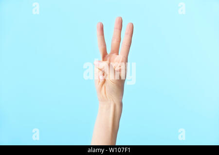 human hand showing number three, isolated on blue background