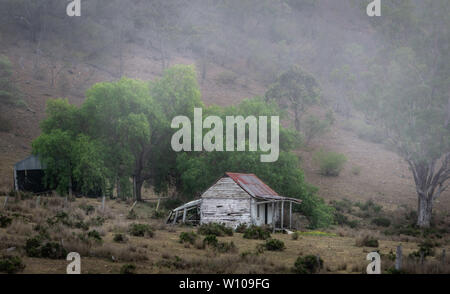 Old Australian farm house in the hills with rain and fog rolling over the hill Stock Photo