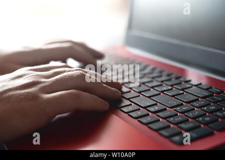 Side view shot of man's hands busy working on his laptop sitting at wooden table Stock Photo