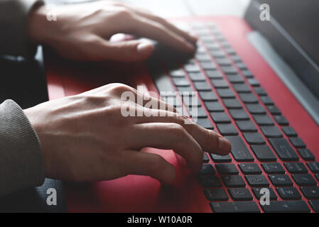 Side view shot of man's hands busy working on his laptop sitting at wooden table Stock Photo