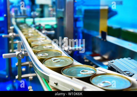 Canned food products on conveyor belt in distribution warehouse.parcels transportation system concept. Stock Photo