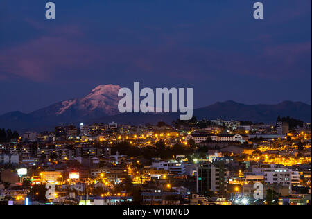 Cityscape of Quito at night with the impressive Cayambe volcano, Andes mountains, Ecuador, South America. Stock Photo