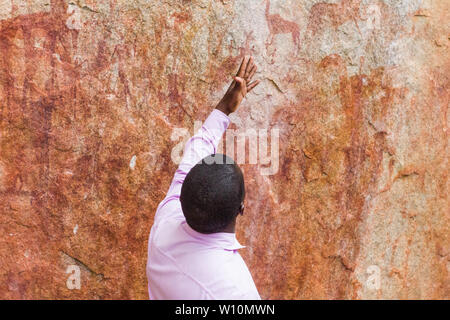 Local historian explaining some 8000 years old rock art paintings in Chinhamapare Hill within Vumba Mountain Range in Mozambique near Zimbabwe border Stock Photo