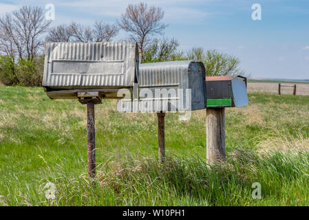 A row of three old metal farmers mailboxes on the prairies in rural Saskatchewan, Canada Stock Photo