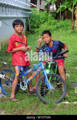 Two boys with their bicycles in Nonthaburi, Thailand, one flashing the ubiquitous V sign Stock Photo