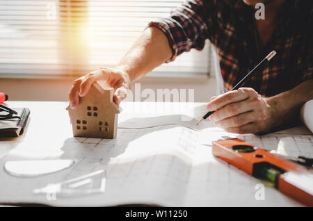 professional architect, engineer or interior hands drawing with house model design, blueprint on workplace desk in office center at construction site Stock Photo