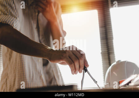 professional architect, engineer or interior hands drawing with divider compass and thinking on workplace desk in office center at construction site Stock Photo