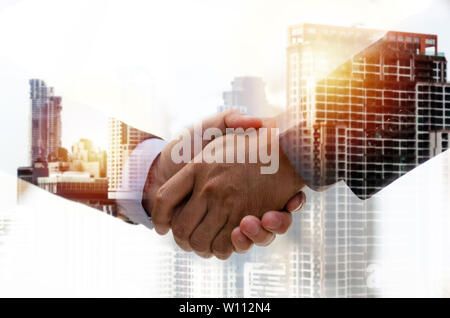 Partnership. double exposure image of investor business man handshake with partner for successful meeting deal with during sunrise and cityscape Stock Photo