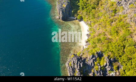Small deserted white sand beach, top view.White beach and azure lagoon near the cliffs on a tropical island. Stock Photo