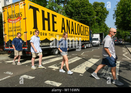 Abbey Road, London, UK.  29th June 2019.  UK Weather:  Tourists crossing the famous Abbey Road zebra crossing made famous by The Beatles on a scorching hot day in London.  A lorry is parked on the road which has advertising on it for 'The Analogues' Beatles musical.  Picture Credit: Graham Hunt Photography. Credit: Graham Hunt/Alamy Live News