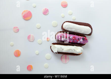 A set of three eclairs with different fillings and design isolate on a white surface decorated with drops of white chocolate, copyspace Stock Photo