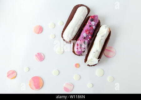 A set of three eclairs with different fillings and design isolate on a white surface decorated with drops of white chocolate, copyspace Stock Photo