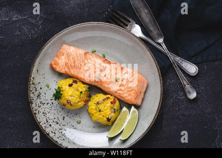 Grilled Salmon Steak with Yellow Risotto and Lime on Stone Background. Healthy Eating Concept. Stock Photo