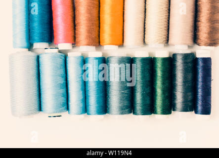 Colored sewing thread coils on white background with copy space for text Stock Photo