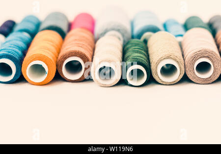 Colored sewing thread coils on white background with copy space for text Stock Photo