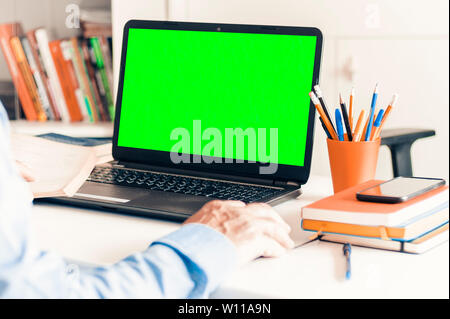 Close-up of hand man using a mouse and typing on green screen laptop on white table, business concept Stock Photo