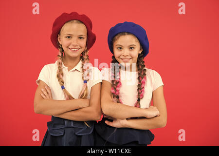 Stylish and confident. Cute girls having the same hairstyle. French style  girls. Small children with long hair plaits. Fashion girls with tied hair  into braids. Little kids wearing french berets Stock Photo -