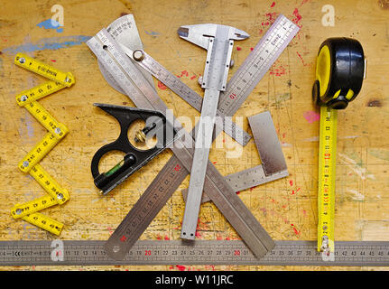 Various metering tools on wooden workbench grunge paint splashed surface. Stock Photo