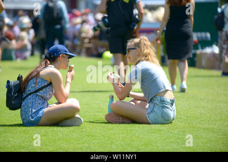 Two girls eat ice cream, Devonshire Park, Eastbourne, UK. 29th June, 2019. Perfect weather for watching the tennis, if perhaps a bit warm to be playing - at Nature Valley International tennis Stock Photo