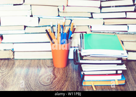 colored pencils in holder with Stack of notebooks on book education concept background Stock Photo