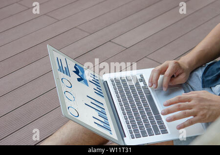 Businessman at work. businessman working sitting outdoors  laptop with graphs, diagrams and charts on screen. Stock Photo