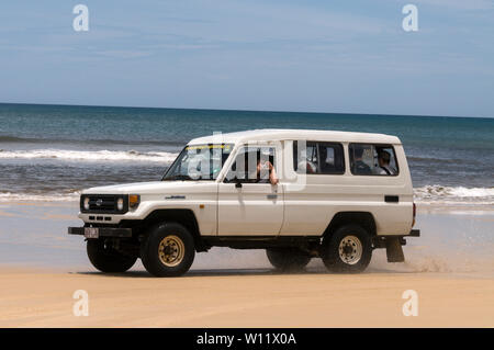 A young tourist carrying 4WD on the 75 mile long Sandy Highway on Fraser Island, Queensland, Australia, facing the South Pacific Ocean.    Fraser Isla Stock Photo