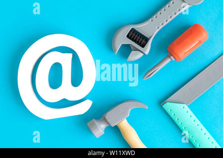 Plastic carpentry tools and email symbol abstract isolated on blue. Stock Photo