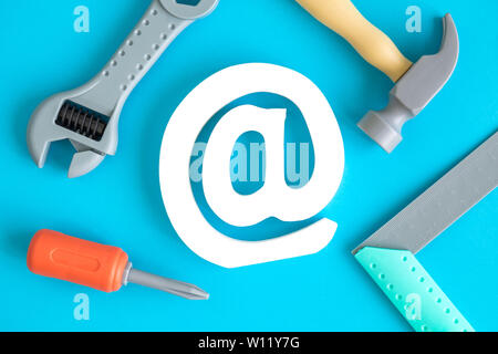 Flat lay of construction tool toys and email sign against blue background minimal creative concept. Stock Photo